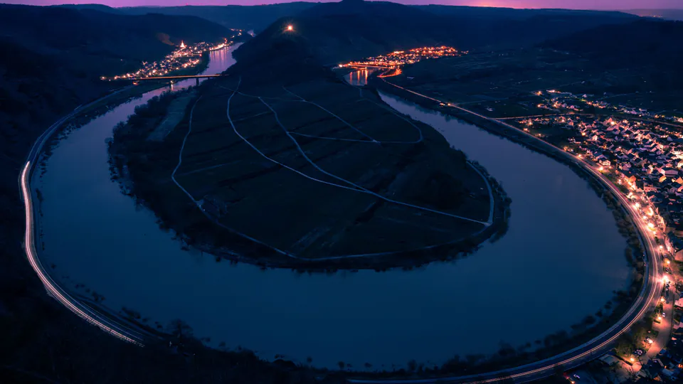 Aerial night view of the Moselle river's horseshoe bend at Bremm, lit by village and road lights